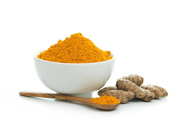 Bowl of turmeric powder with fresh turmeric root